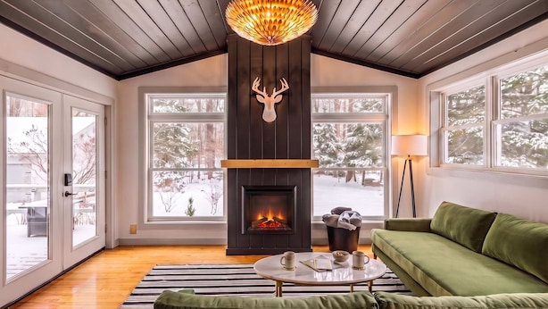 A cozy room with a fireplace, a green sofa, and a chandelier. - Artist Bluff — Signature King Suite with Living Room & Fireplace (Lincoln)