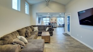 A spacious living room with a large sectional sofa, a coffee table, and a flat-screen TV mounted on the wall. - Green Bay Getaway Near Lambeau Field & Resch! (Green Bay)