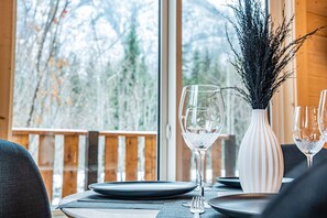 Une table à manger dressée avec des assiettes, des verres et un vase contenant des branches.