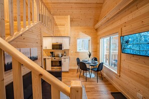 L’intérieur d’un chalet en bois comprend une cuisine, un coin repas et un escalier.