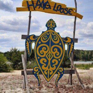 Une enseigne représentant une tortue et portant l’inscription « Hang Loose », fixée à un poteau en bois.