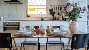 Een eettafel gedekt met borden, glazen en een bloevas.