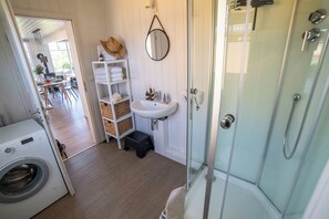 Een badkamer met een glazen douche, een wastafel en een wasmachine.