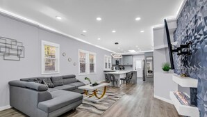 A modern living room with a grey sectional sofa, a white coffee table, and a dining area with a kitchen in the background. - Spacious House in Charlotte Close to NoDa District (Charlotte)