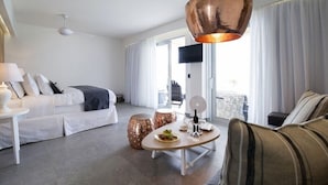 A modern hotel room with a bed, sofa, dining table, and a large window. - Insula Alba Resort and Spa - Adults Only (Hersonissos)