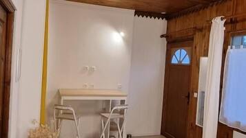 A bedroom with a wooden ceiling, a bed, a desk with two chairs, and a window with curtains.
