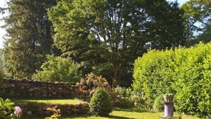 A garden with a stone wall, a neatly trimmed hedge, and a variety of plants and flowers. - Les Tables Aux Vaches (La Salvetat-sur-Agout)