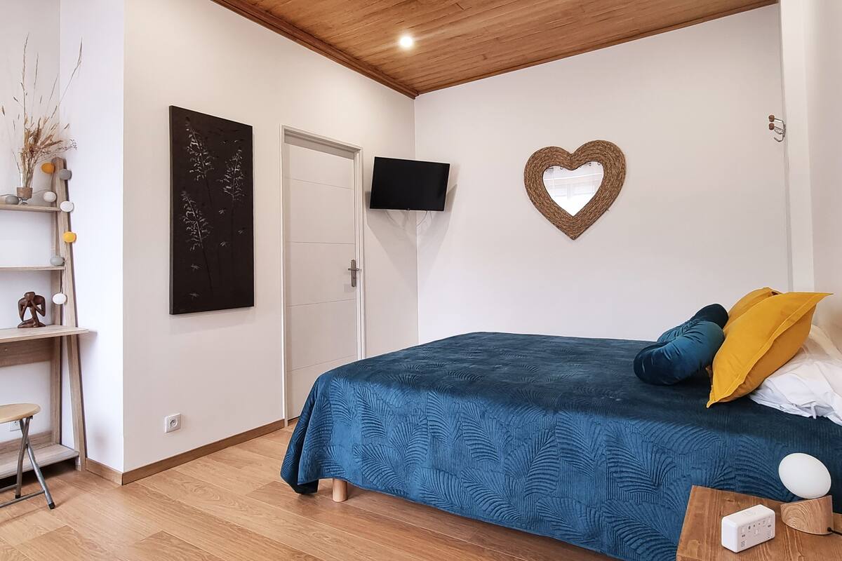 Une chambre à coucher avec un lit, une télévision, une décoration en forme de cœur et une étagère avec des objets décoratifs.