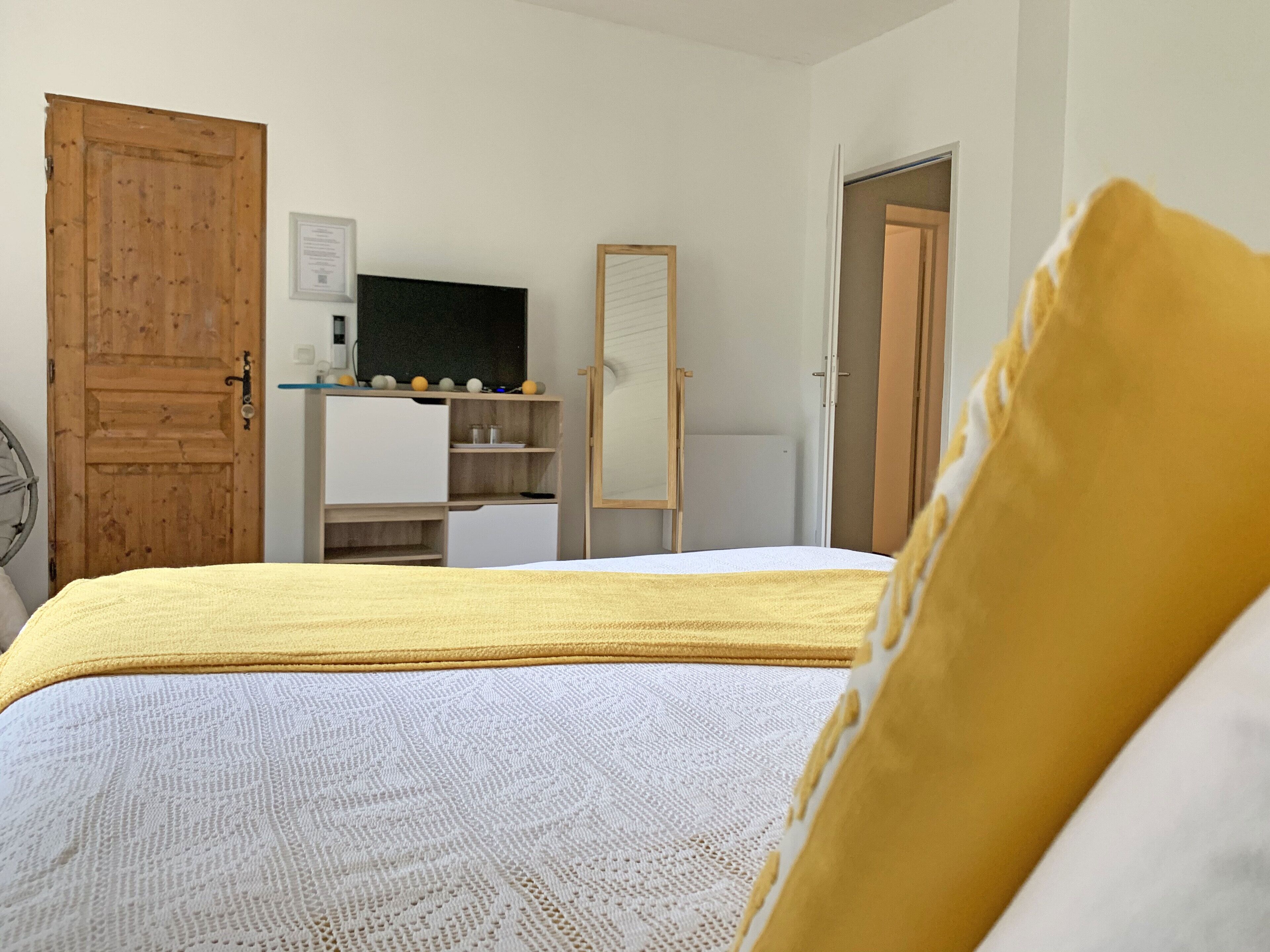 Ein Schlafzimmer mit einem Bett, einem Holzschrank, einem Schreibtisch mit Computer und einem Spiegel.