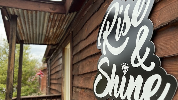 En mur af træ med et skilt, der siger "Rose & Shine".