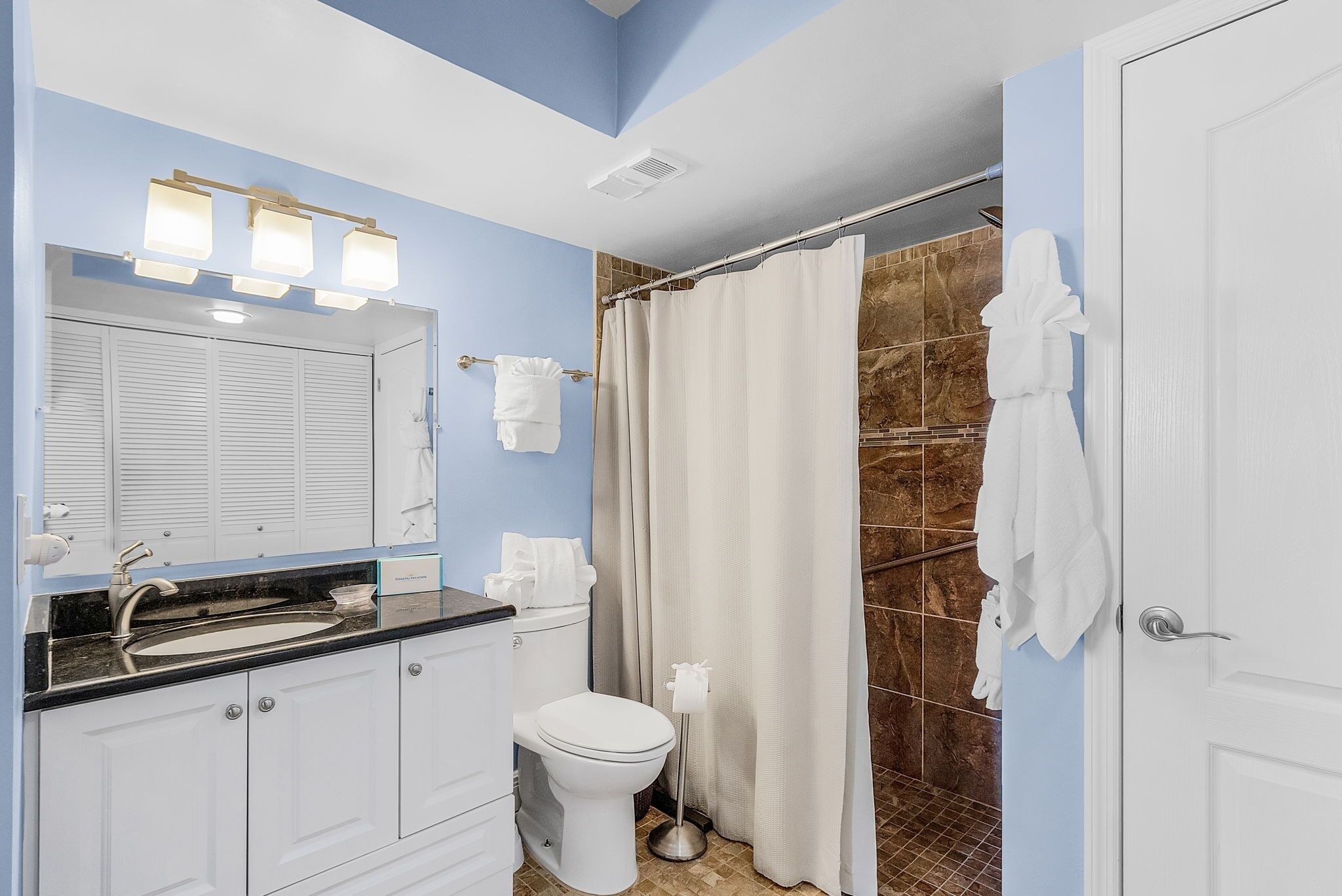Un baño con lavamanos blanco, inodoro y cortina de ducha.