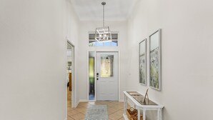 Um corredor com uma porta branca, um console branco com cestos e um tapete cinza estampado.