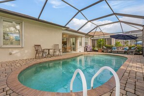 An indoor swimming pool with a glass ceiling, surrounded by patio furniture and potted plants. - Sunshine Daydream Our Beautiful Monthly Pool Home! 3 Bedroom Home by RedAwning (Fort Myers)