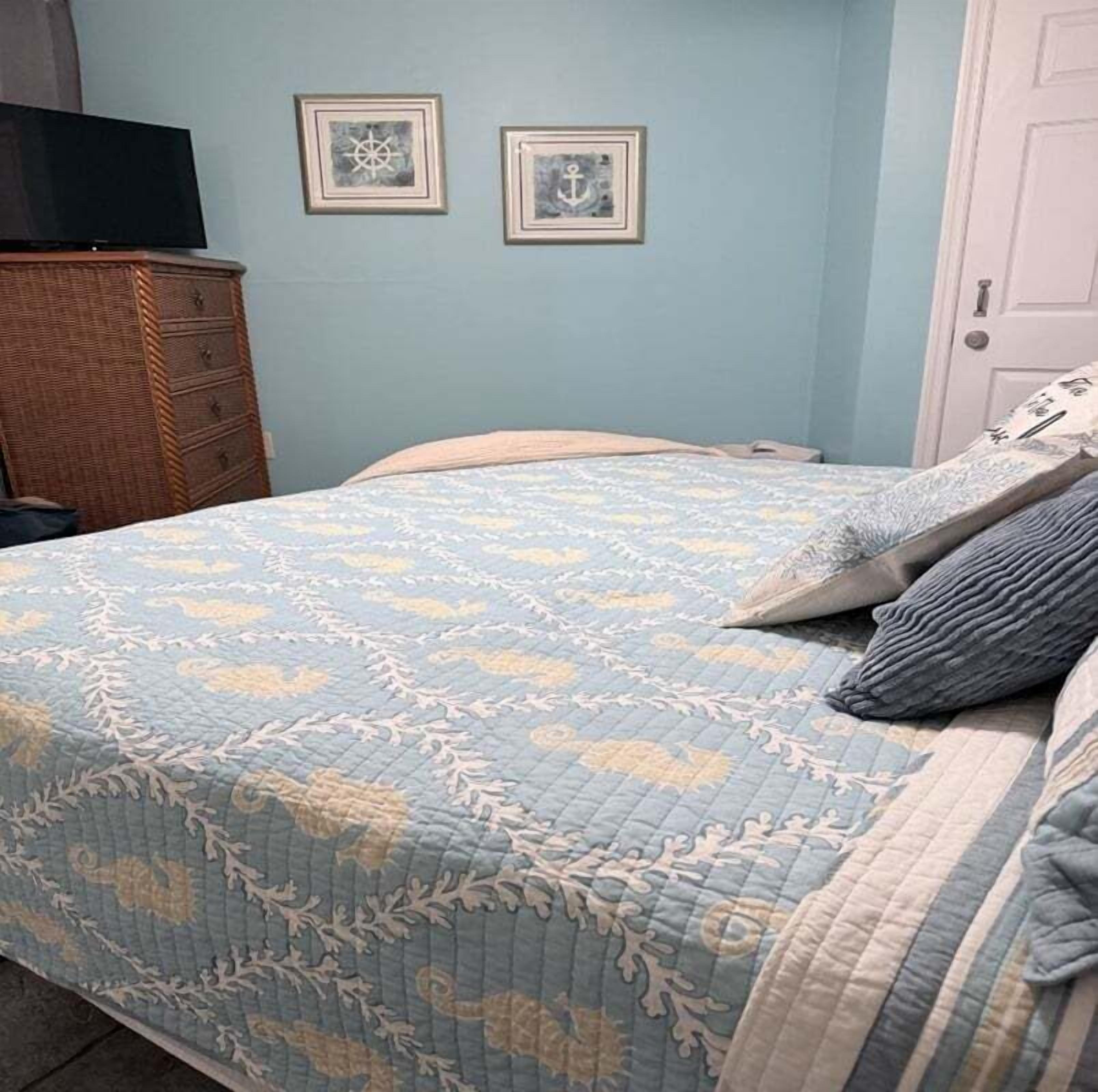 A bedroom with a bed, dresser, and two framed pictures on the wall.