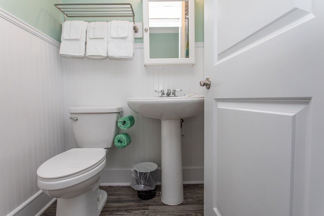A bathroom with a toilet, sink, and a towel rack with towels.