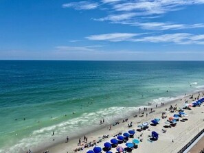 A beach with clear blue water, a sandy shore, and numerous umbrellas. - Royal Garden Resort 815 2 Bedroom Condo by RedAwning (Murrells Inlet)