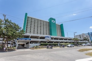 A hotel with a green and white facade, a parking garage, and a sign for the Royal Garden Resort.