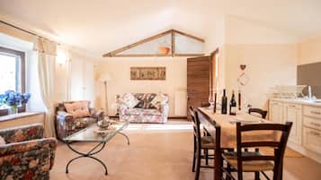 A cozy living room with a sofa, a coffee table, and a dining area with chairs and a table.