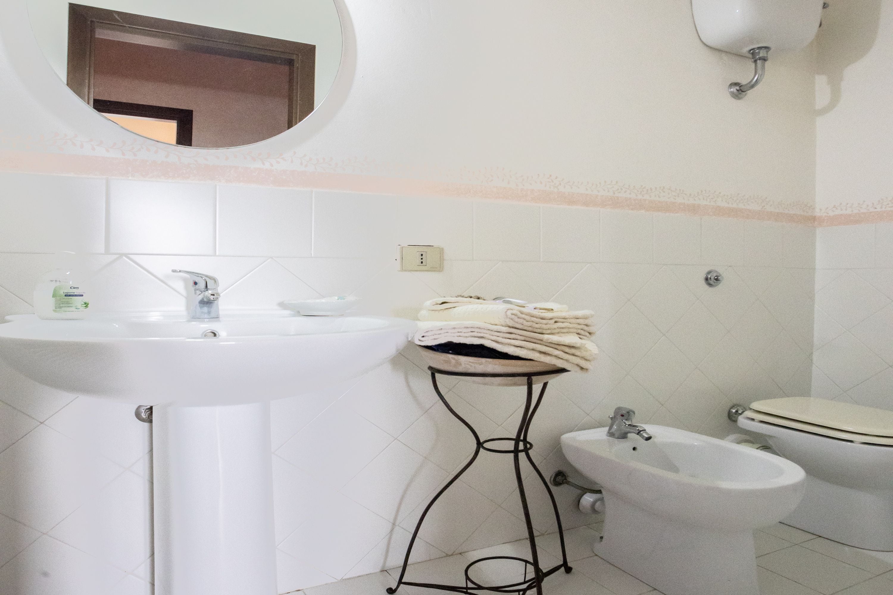 A bathroom with a sink, bidet, toilet, and a towel rack.