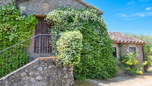 A stone building with a wooden door, a staircase, and a small garden area.
