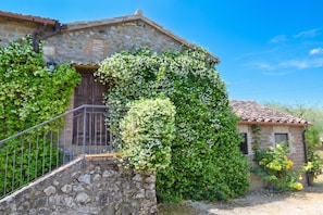 Un bâtiment en pierre avec une porte en bois, un escalier et un petit jardin.