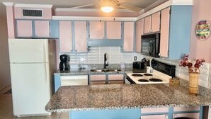 A kitchen with a central island, a refrigerator, a microwave, and a ceiling fan. - Royal Garden Resort 914 2 Bedroom Condo by RedAwning (Murrells Inlet)
