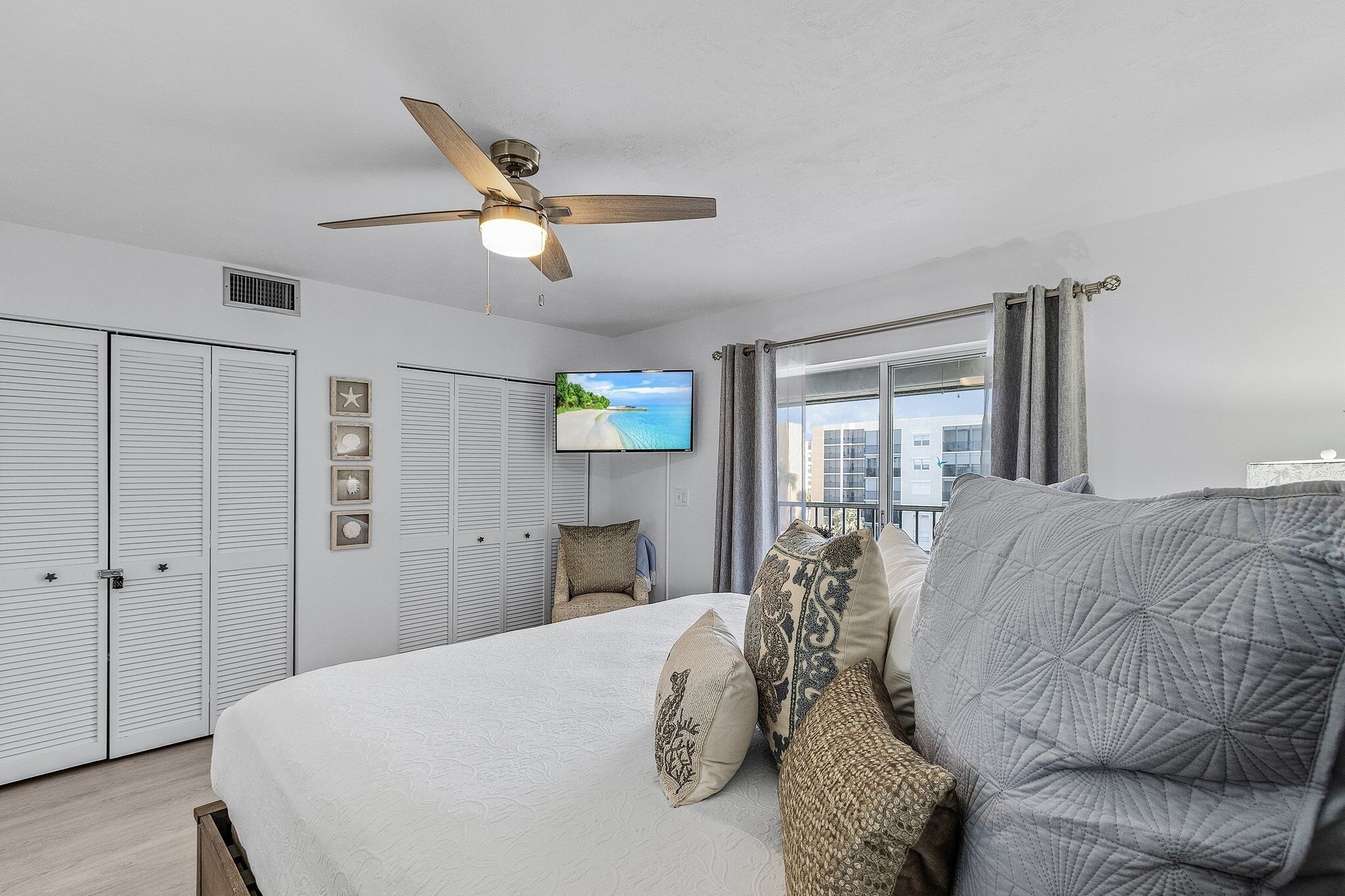 Une chambre avec un lit, un ventilateur de plafond, une télévision et une vue sur l’extérieur.