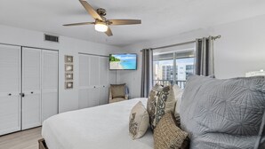 Une chambre avec un lit, un ventilateur de plafond, une télévision et une vue sur l’extérieur.