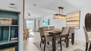 Un coin repas avec une table et des chaises en bois, une bibliothèque turquoise et un téléviseur fixé au mur.