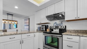 Une cuisine moderne avec des meubles blancs, un four en acier inoxydable et un plan de travail en granit.