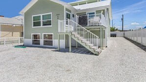 A two-story house with a staircase, a covered porch, and a gravel driveway. - Welcome To Coconut Dreams Fantastic Vacation Rental - 2633 Estero Blvd Unit A 3 Bedroom Home by RedAwning (Fort Myers Beach)