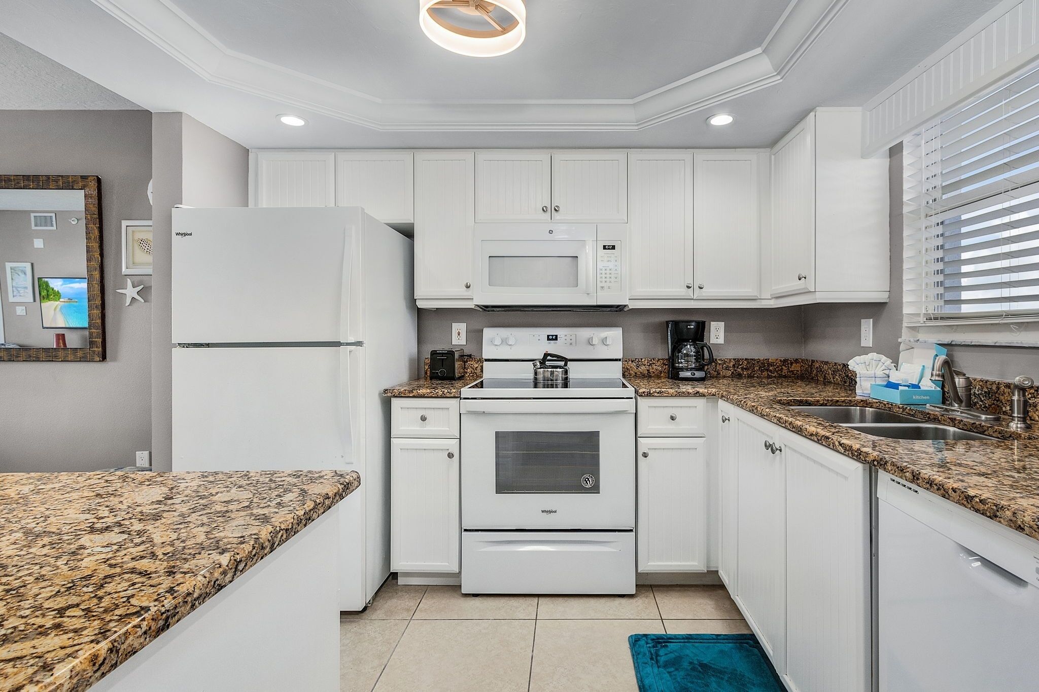 A modern kitchen with white cabinets, granite countertops, a built-in microwave, and a stove.