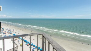 A beach with umbrellas and people, a clear sky, and the ocean. - Royal Garden Resort 1003 1 Bedroom Condo by RedAwning (Murrells Inlet)
