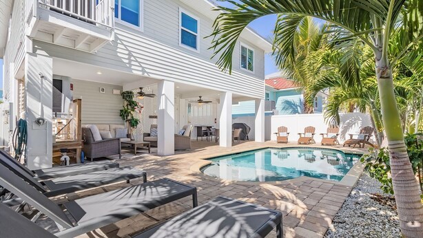 A poolside area with lounge chairs, a covered seating area, and a pool. - Welcome To 246 Delmar Ave - Vacation Rental 3 Bedroom Home by RedAwning (Fort Myers Beach)