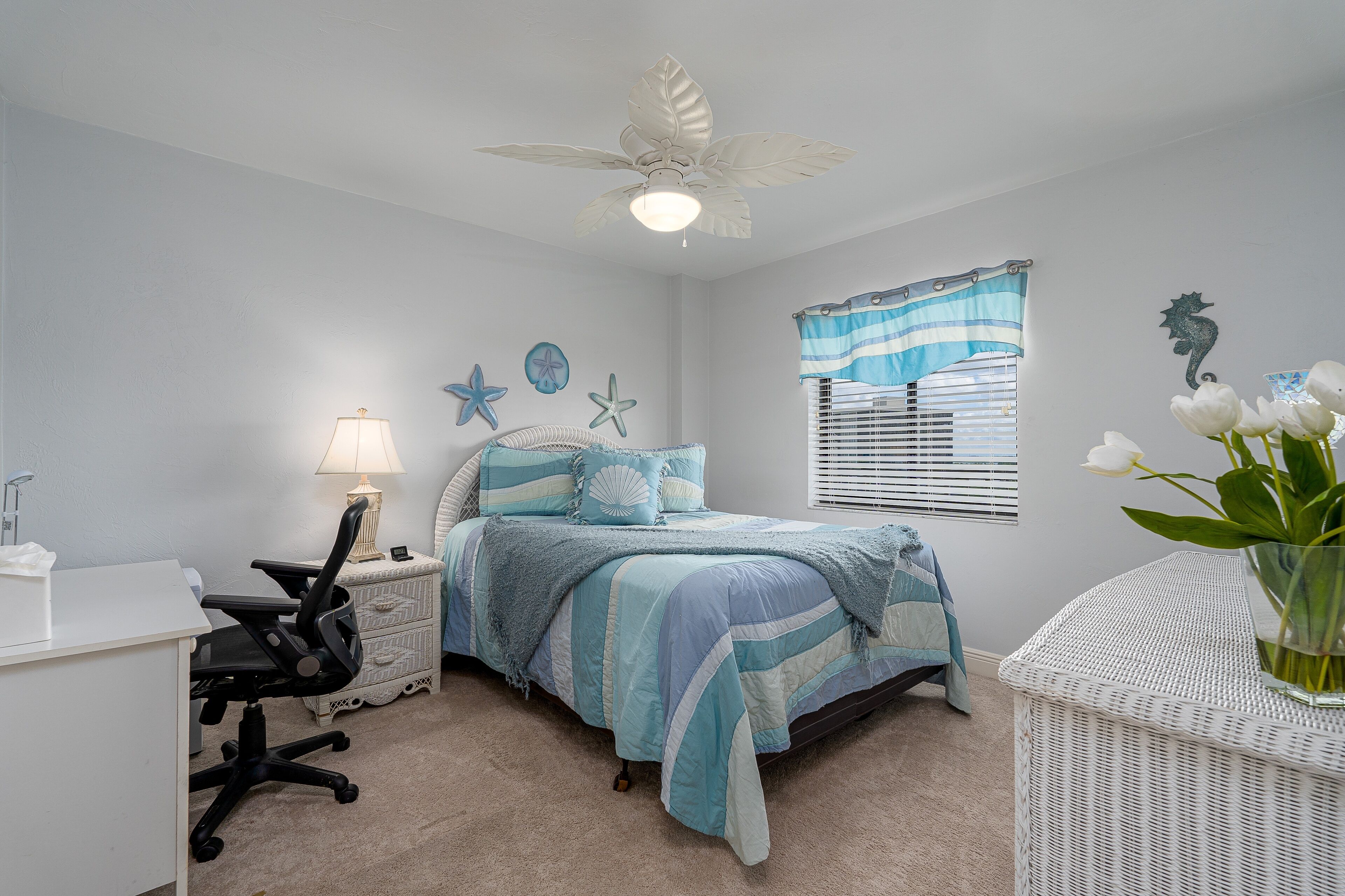 A bedroom with a bed, desk, chair, and a ceiling fan.