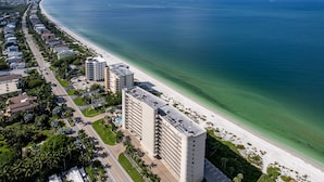 Ett flygbildsfoto av ett hotell vid kusten, med en strandpromenad, flera våningar och en väg som löper parallellt med stranden.