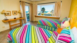 A room with two beds, a desk, and a window with curtains. - Spectacular 2 Bedroom Condo on Sandy Beach at Las Palmas Resort B-203 2 Condo by RedAwning (Puerto Peñasco)