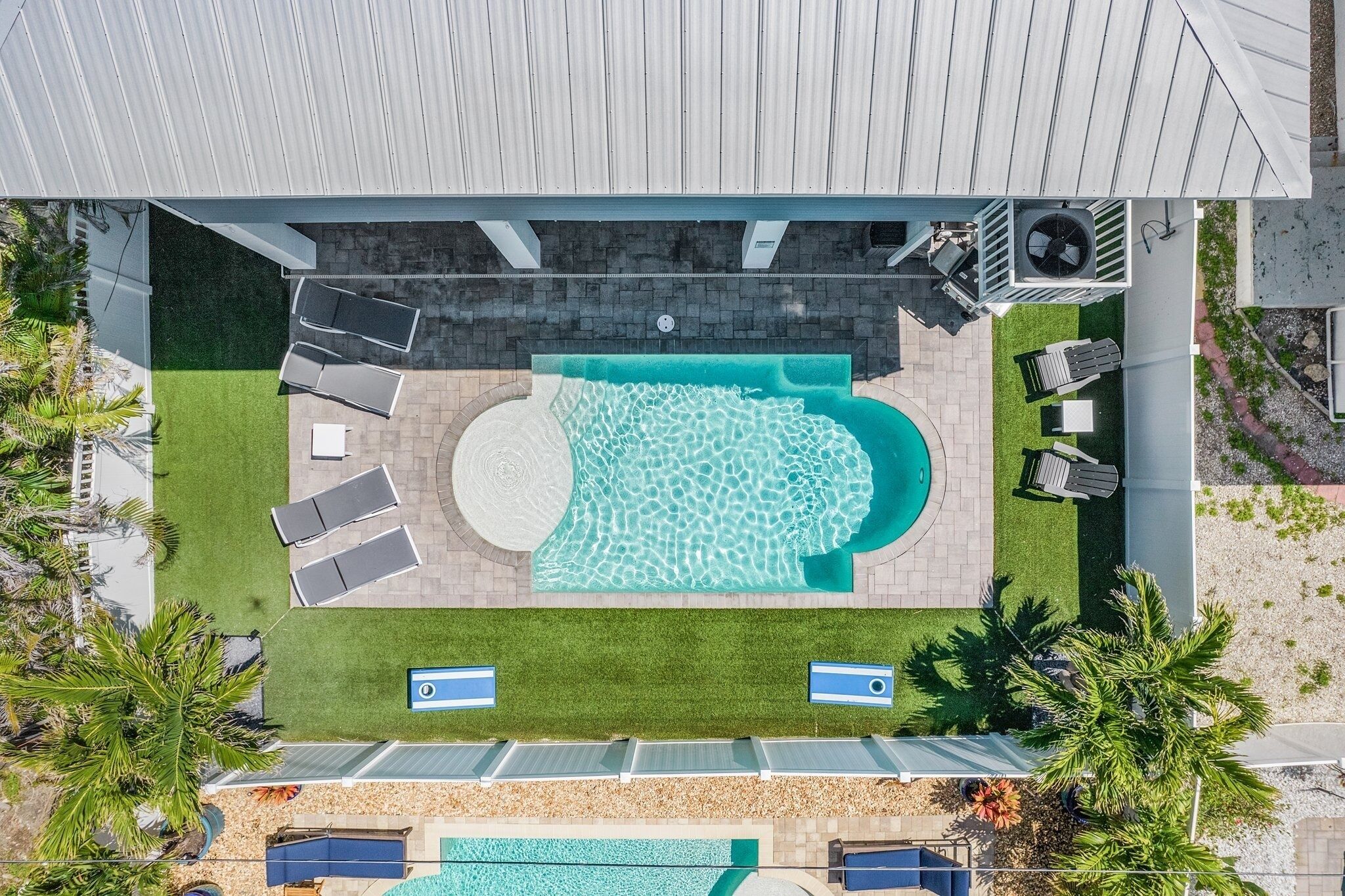 Ein Luftbild eines Poolbereichs auf einem Dach mit großem Pool, Liegestühlen und einem kleinen Wasserfall.