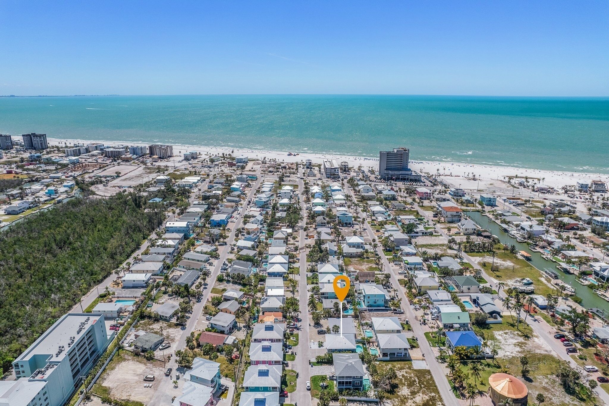 Vista aérea de una zona residencial costera, con playa, casas y un edificio grande.