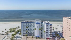 A beachfront hotel with a view of the ocean. It features multiple floors with balconies, a parking area, and a pool. - Beach Villas # 305 - Recently Refereshed! 2 Bedroom Condo by RedAwning (Fort Myers Beach)