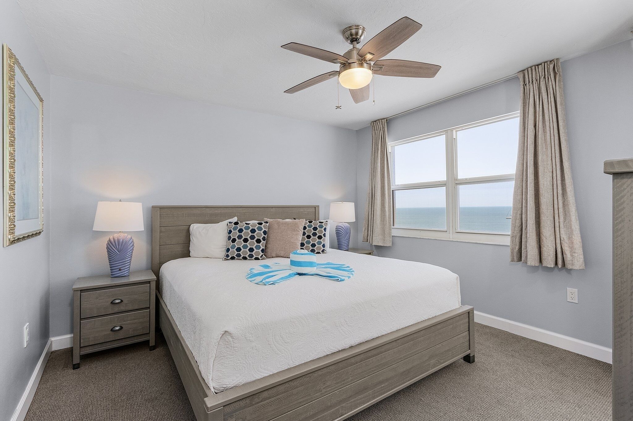 A bedroom with a bed, nightstands, a ceiling fan, and a window with curtains.