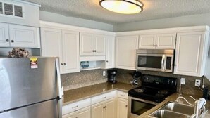 A kitchen with white cabinets, a stainless steel refrigerator, a microwave, and a stove.
