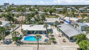 A residential area with a swimming pool, houses, and palm trees. - 171 Washington ~ Dune Our Thing ~ Unit A ~ Fabulous Pool Home! 2 Bedroom Home by RedAwning (Fort Myers Beach)