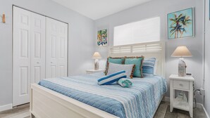 A bedroom with a bed, nightstands, a wardrobe, and artwork on the walls. - 171 Washington ~ Dune Our Thing ~ Unit A ~ Fabulous Pool Home! 2 Bedroom Home by RedAwning (Fort Myers Beach)