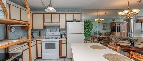 A kitchen with wooden cabinets, a white stove, and a dining area with a large table and chairs.