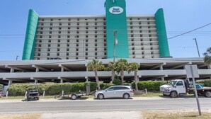 A hotel with a prominent green and white color scheme, multiple floors, and a parking garage below. - Royal Garden Resort 803 1 Bedroom Condo by RedAwning (Murrells Inlet)