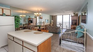 A spacious living area with a large dining table, a sofa, and a bed with a view. - Royal Garden Resort 803 1 Bedroom Condo by RedAwning (Murrells Inlet)