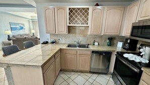 Una cocina moderna con armarios color beige, un lavavajillas de acero inoxidable, un horno negro y un microondas.