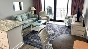 A modern living room with a sofa, armchair, coffee table, and a dining table.