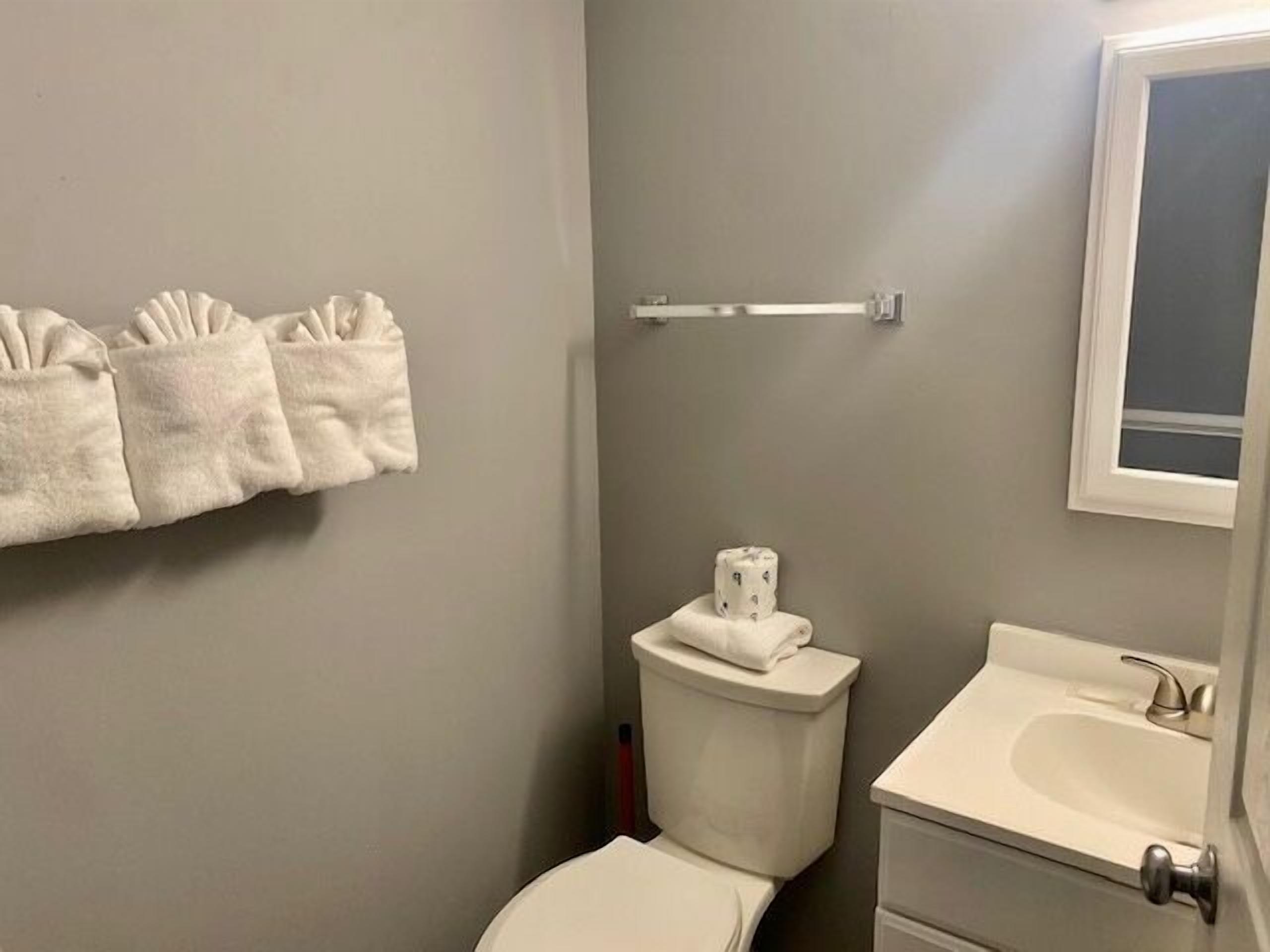 Une salle de bain équipée de toilettes, d’un lavabo et d’un porte-serviettes avec des serviettes pliées.